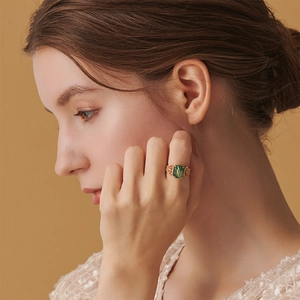Macro detail of gold vintage ring with rectangular green stone and filigree craftsmanship