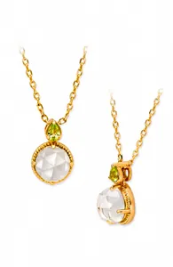 Details einer Goldkette mit rundem weißem Stein und grünem Peridot-Anhänger
