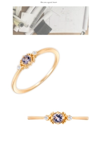 Detail macro of a gold ring with a round lavender gemstone and side white accents