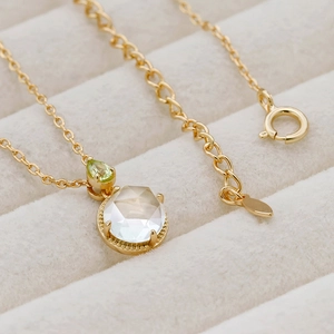 Makro-Detail der 14k vergoldeten Silberkette mit grünem Edelstein und Hexagon-Kristall