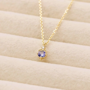 Détail d'un collier en argent S925 doré avec tanzanite et zircon sur un support en velours