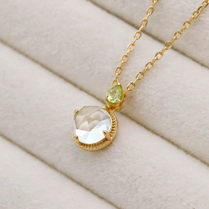 Makro-Detail der 14k vergoldeten S925 Silberhalskette mit grünem Peridot und weißem Kristall