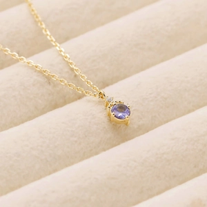 Vue macro d'un collier en chaîne dorée avec un pendentif en tanzanite lavande facettée