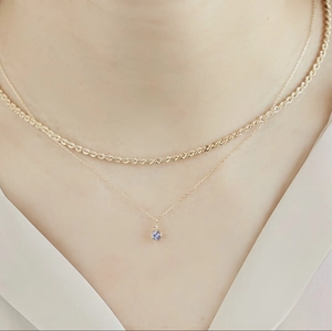 Détail du collier superposé en maille corde dorée et pendentif gemme lilas élégant