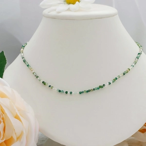 Detailed macro of beaded necklace with green moss agate and gold beads on neck model