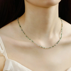 Detail of elegant S925 silver beaded necklace with green agate and gold accents on neck