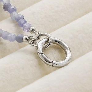 Détail macro de perles facettées violettes avec fermoir argenté texturé sur le bijou