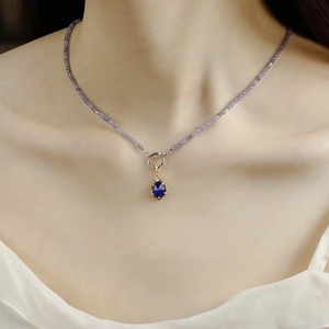 Détail d'un collier de perles avec pendentif ovale bleu serti sur griffes en or