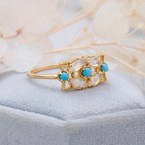 Vue macro d'une bague vintage dorée avec turquoise et opales au design ajouré