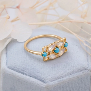 Bague vintage dorée avec turquoise et opale sur un écrin à bijoux en velours bleu