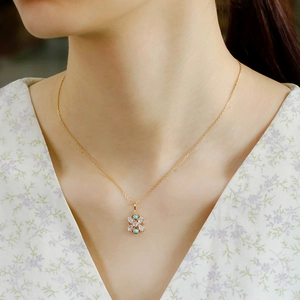 Primer plano de un colgante floral vintage en plata S925 con ópalo y turquesa en cadena oro