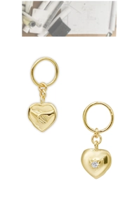 Detail view of 14K gold plated heart pendants with handshake relief and sparkling star set stone