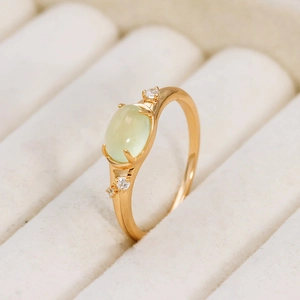 Macro shot of oval prehnite gemstone ring with gold plating and zircon accents