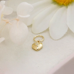 Macro shot of 14K gold-plated heart pendant with sparkling gemstone on a white flower