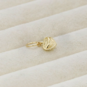 Macro shot of gold-plated 14K vintage heart pendant with embossed praying hands detail