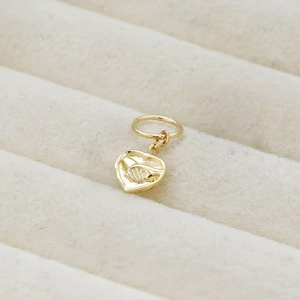 Macro shot of 14K gold plated heart pendant with embossed hands holding pattern