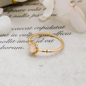 Macro detail of gold-plated silver ring with moonstone and cubic zirconia on vintage paper