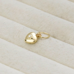 Macro detail of 14K gold plated S925 silver heart pendant with starburst set zircon