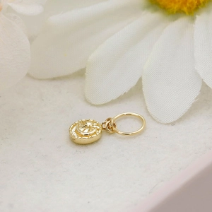 Macro shot of 14K gold-plated star and moon round pendant next to white daisy flowers