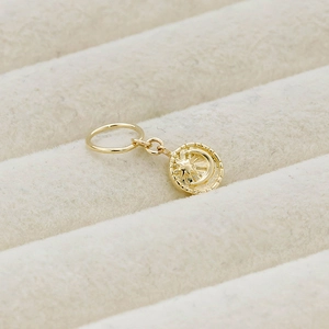Detailed view of a 14K gold-plated star and crescent moon pendant on beige velvet