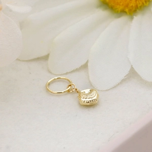 Macro shot of 9K gold vintage square pendant earring with G9K engraving on white petals