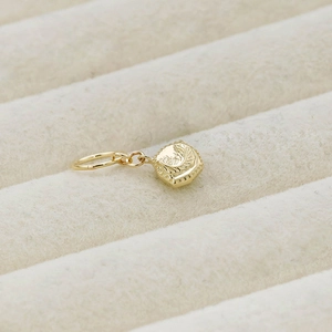 Macro view of gold square pendant with moon and star engraving on beige velvet