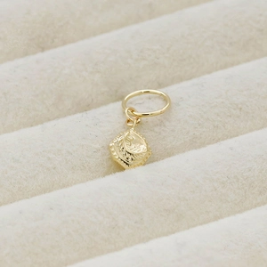 Macro shot of gold square pendant with moon engravings on beige velvet box