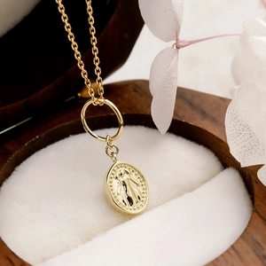 Close-up of a 14K gold plated oval religious medallion on a delicate necklace chain