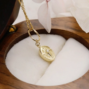 Macro shot of a vintage 14K gold plated double-sided oval pendant with a zircon center