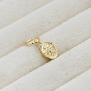 Macro detail of oval 14K gold-plated vintage pendant with engraved star and zircon
