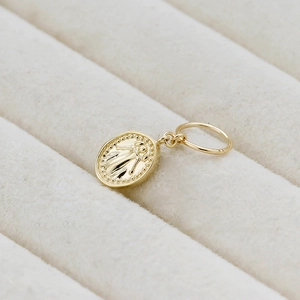 Macro shot of 14K gold plated S925 silver oval pendant with embossed figure design