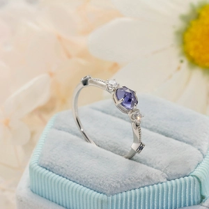 Detail of a purple hexagonal gemstone ring with zircon accents in a blue velvet box