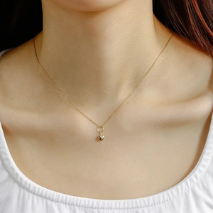 Detail view of a 14K gold-plated double-sided heart pendant on a delicate O-chain