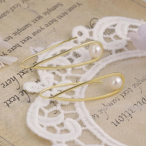 Close-up of gold plated silver earrings with teardrop hollow frame and natural pearls