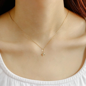 Close-up of a delicate 14K gold plated heart pendant necklace on a model neck