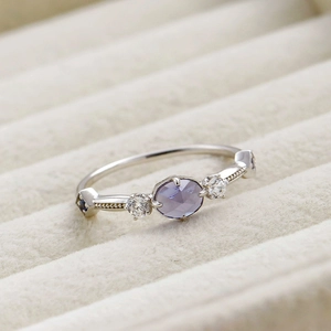Macro shot of silver ring featuring oval violet gemstone and delicate pavé settings