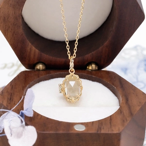 Close-up of gold plated vintage locket necklace with green gemstone in a walnut box