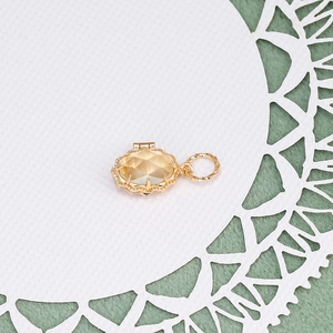 Macro view of a gold-plated vintage locket featuring a faceted amber gemstone