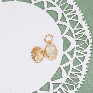 Macro detail of vintage gold locket pendant with oval gemstone on white lace