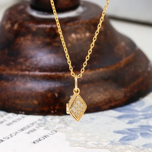 Detail van de dubbelzijdige openklapbare diamant hanger aan een 14k vergulde ketting
