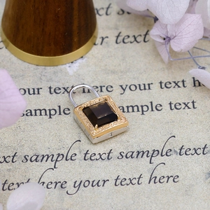 Detail of vintage 14K gold-plated padlock pendant with intricate engravings and dark gem