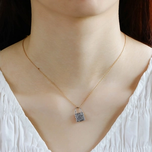 Detailed view of a vintage silver lock pendant with engraving on a gold necklace chain