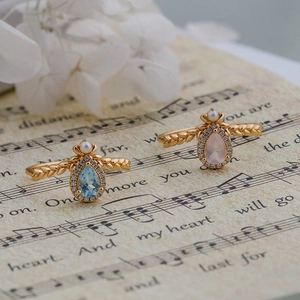 Detail of gold rings with teardrop blue topaz and pink quartz plus small pearls