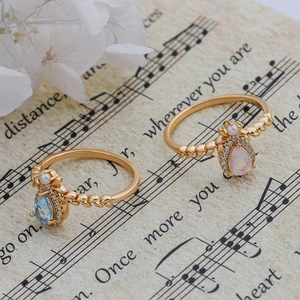 Detail of gold leaf band rings with pear-cut pink and blue crystals and tiny pearls