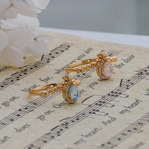 Detailed macro of gold drop-shaped gemstone rings with pearl accents and wheat textures