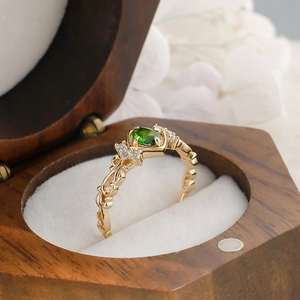 Macro shot of vintage gold ring with oval green stone and side diamonds in a wood box