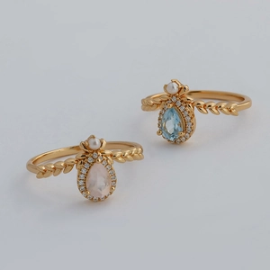 Close-up of gold leaf-textured ring bands with pear-cut pink and blue gemstones