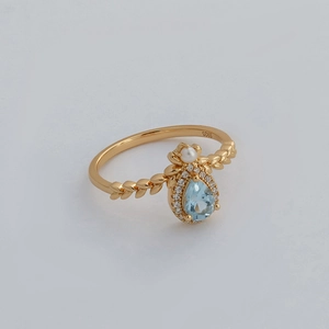 Detail of S925 silver gold-plated ring with sky blue topaz and pearl accent