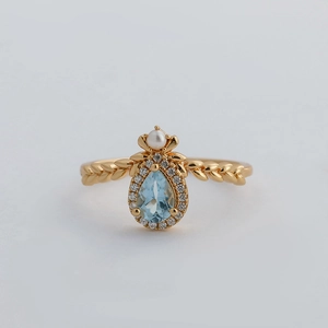 Elegant 14k gold plated silver ring with pear-shaped blue topaz and white pearl detail