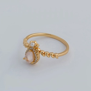 Detailed macro view of pear-shaped pink gemstone ring with pearl and leaf texture band